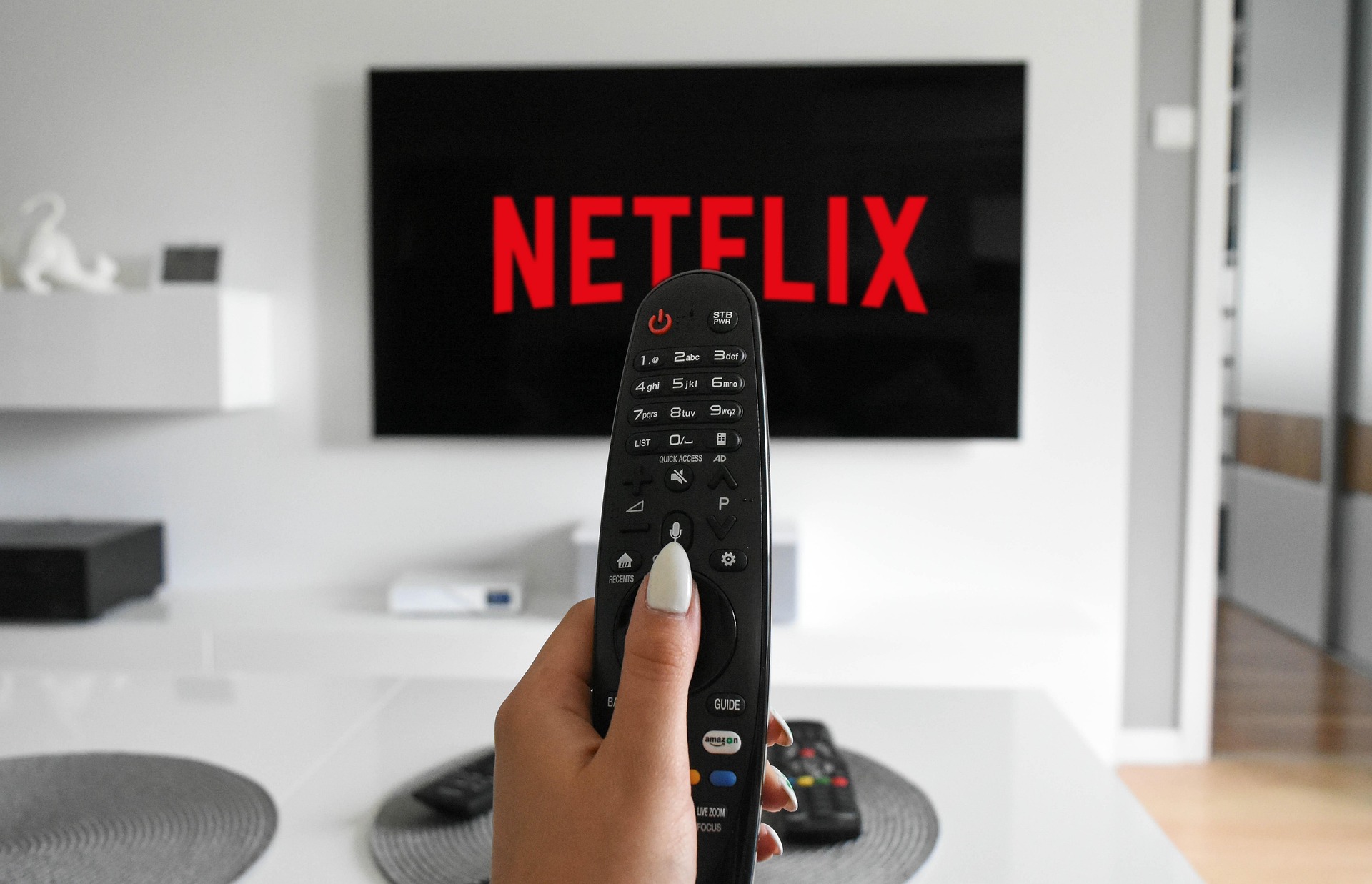 Télécommande tenue devant un téléviseur affichant Netflix dans un salon